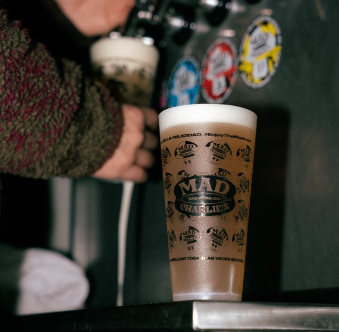 Vaso de Mad Charlie&rsquo;s recién servido sobre la barra, con las llaves detrás