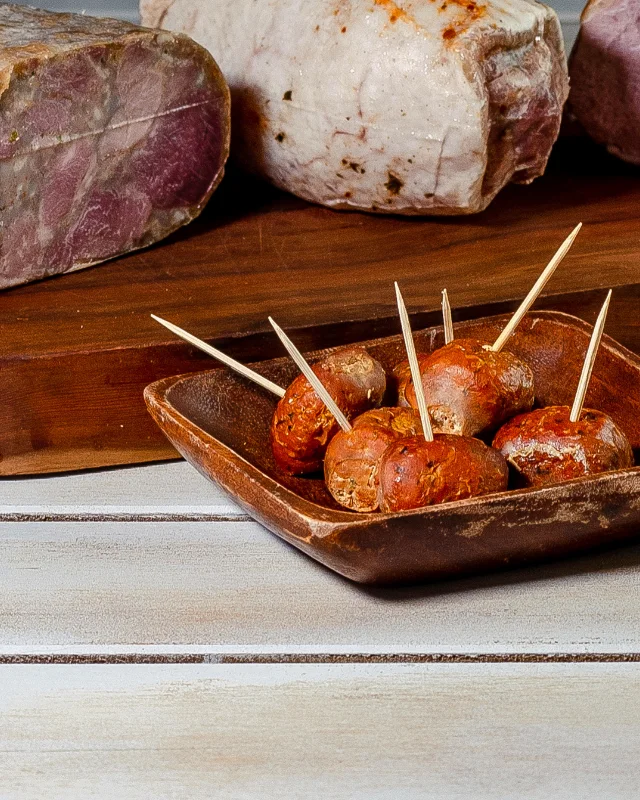 Longaniza Bom-Bom de Cecinas Grau en brochetas, en un bol de madera